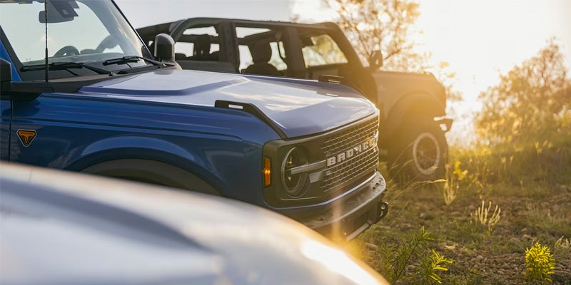 Close-up of a blue 2024 Ford Bronco and two other Broncos