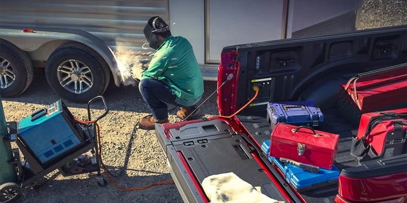 A person plugging a welder in a 2024 Ford F-150 to fix a camper